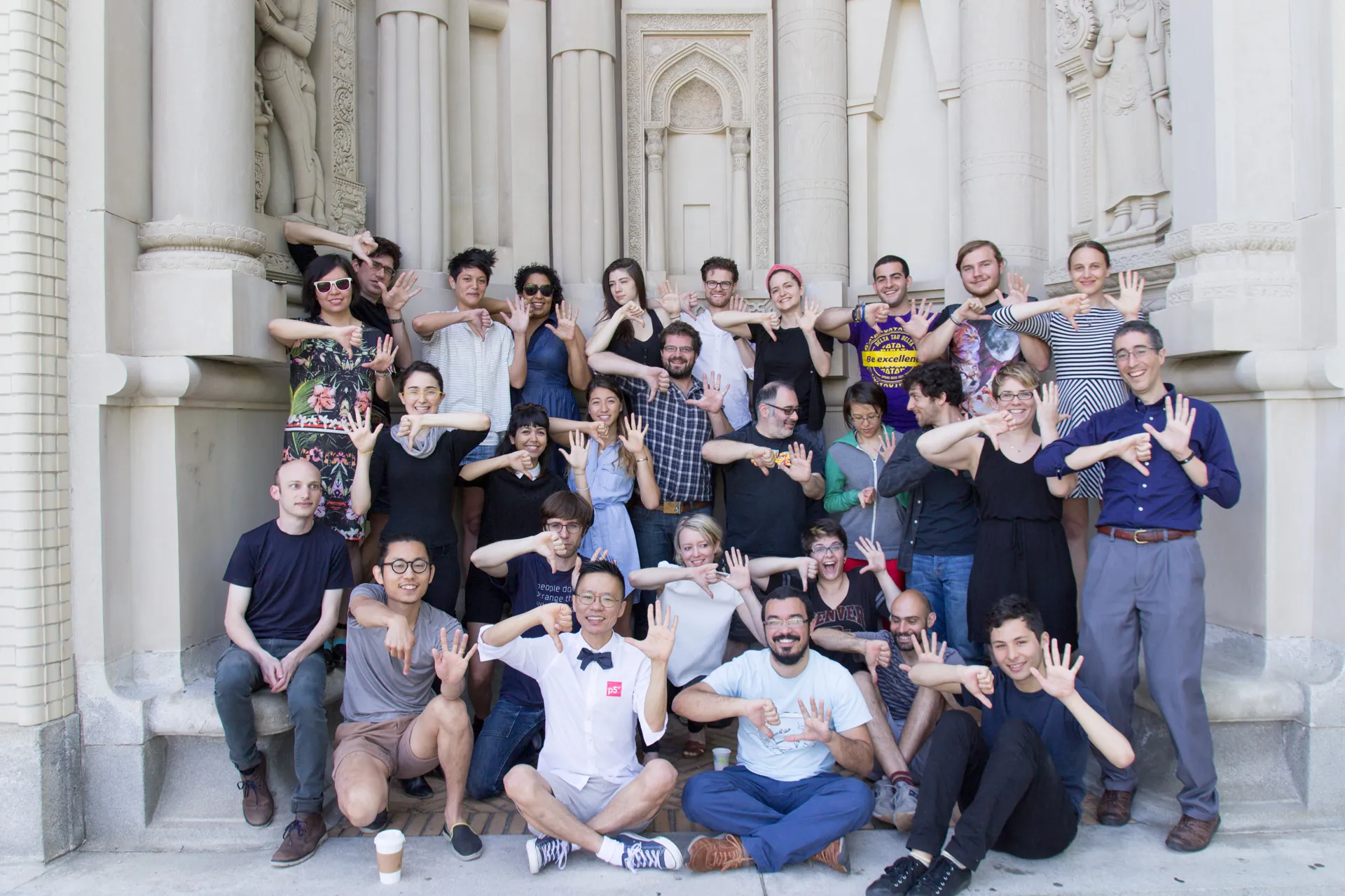 A group of participants smile and make a p5 sign with their hands.