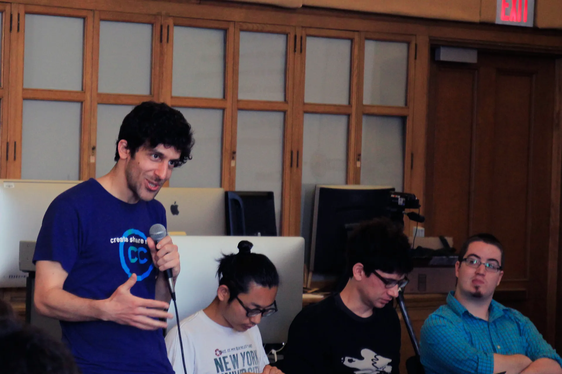 Man in a classroom with a microphone speaking out to a group of participants