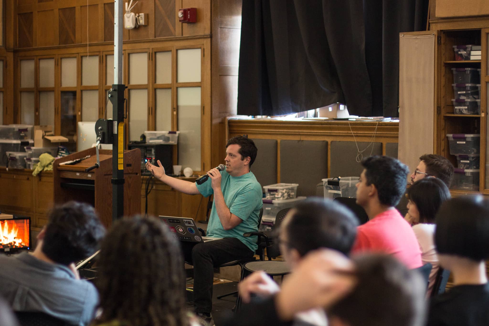 Man sitting in front of the classroom speaking energetically into a microphone