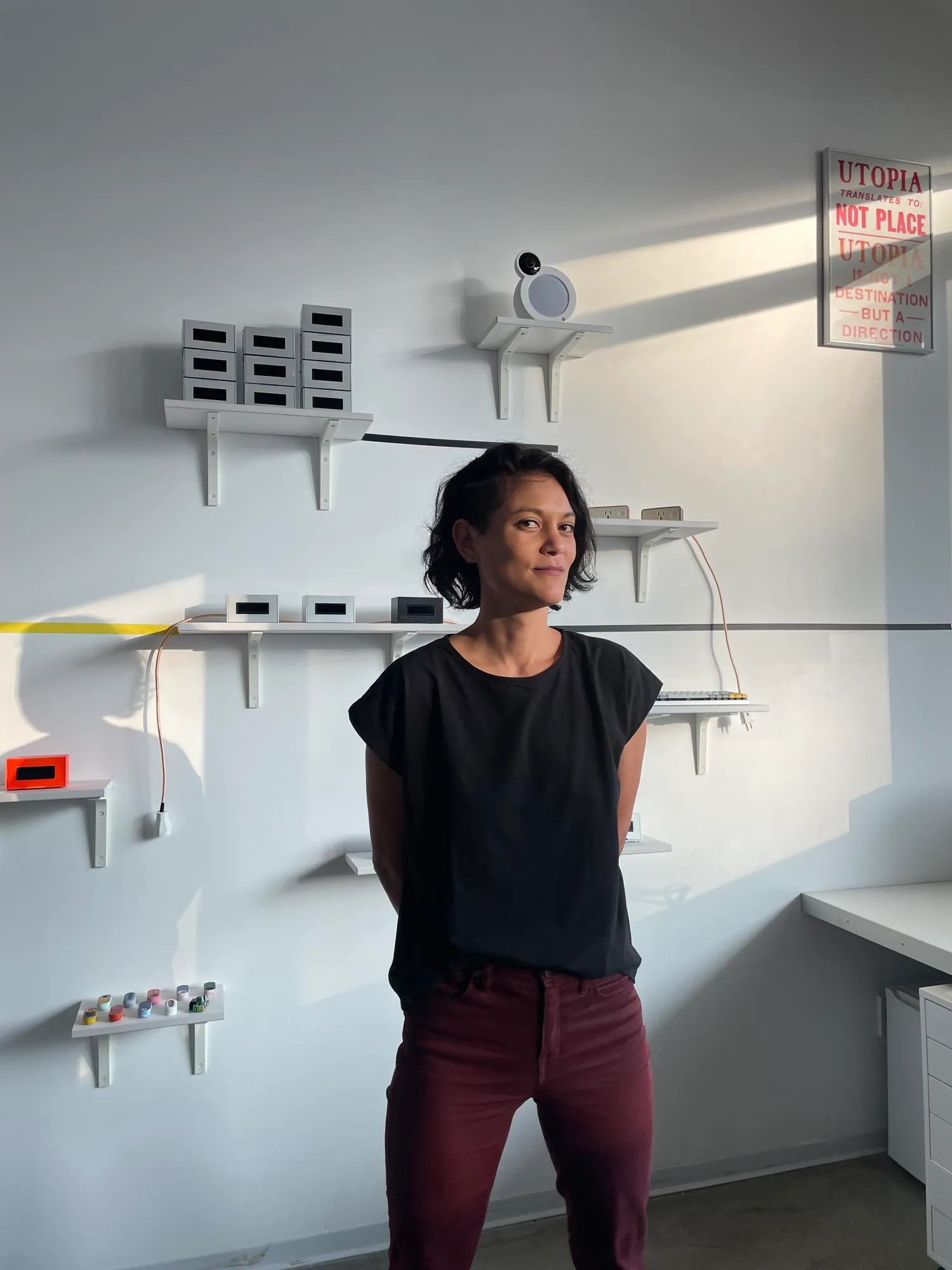 A Chinese-American woman with short dark hair standing in front of device sculptures.